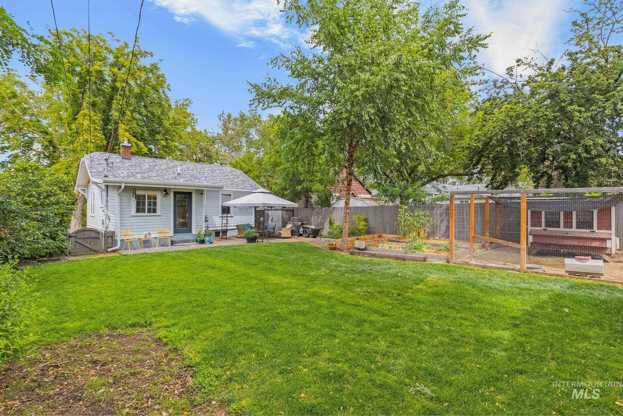 Expansive backyard featuring a lush lawn, a patio area, and a dedicated garden with raised beds