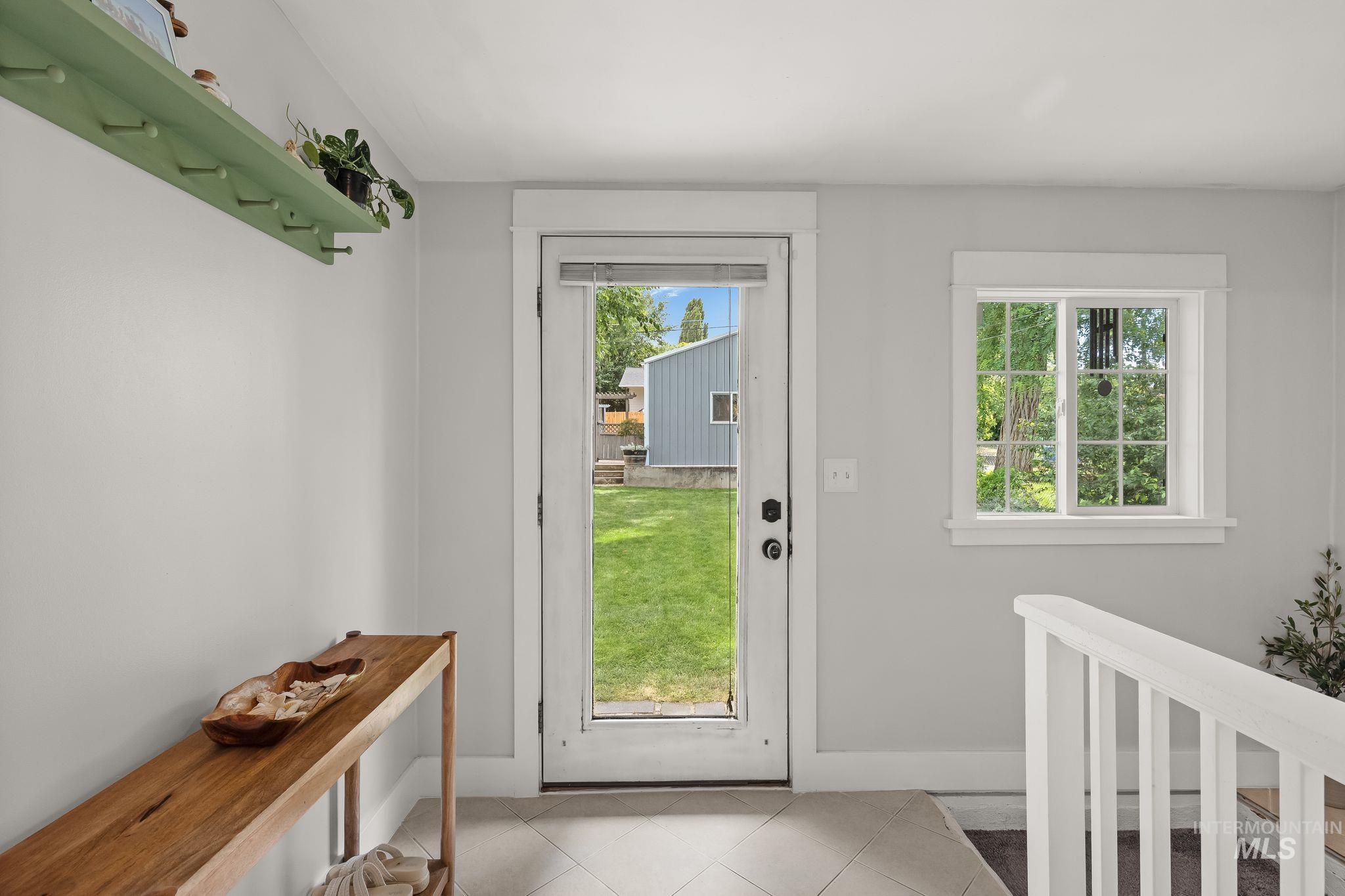 Full-light entry door with interior grid window, tile flooring, and light gray wall paint