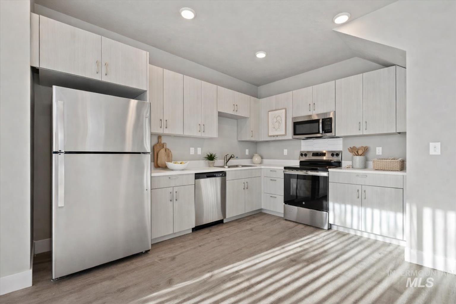 Kitchen featuring stainless steel appliances, light countertops, light wood-style floors, and recessed lighting