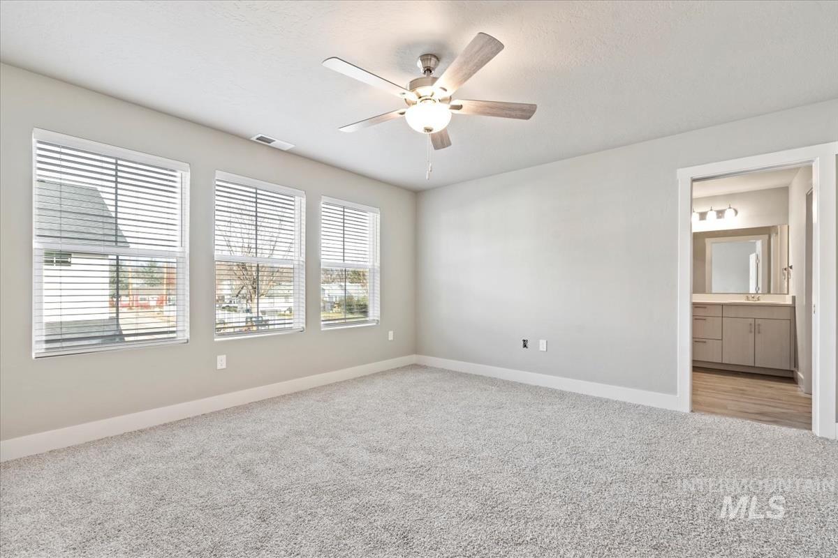 Empty room with light colored carpet and a ceiling fan