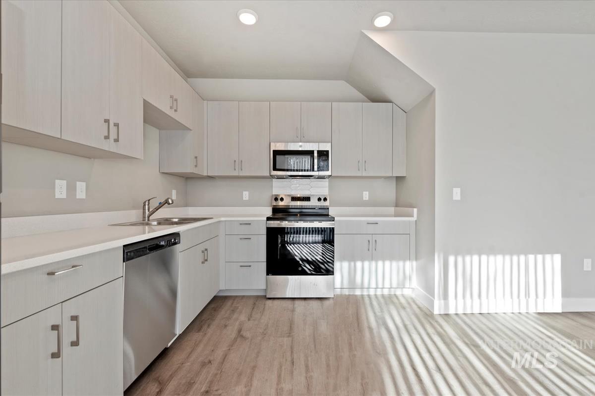 Kitchen with appliances with stainless steel finishes, light countertops, and light wood finished floors