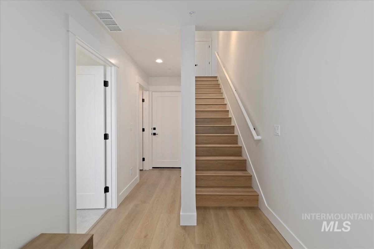 Stairway with wood finished floors and recessed lighting