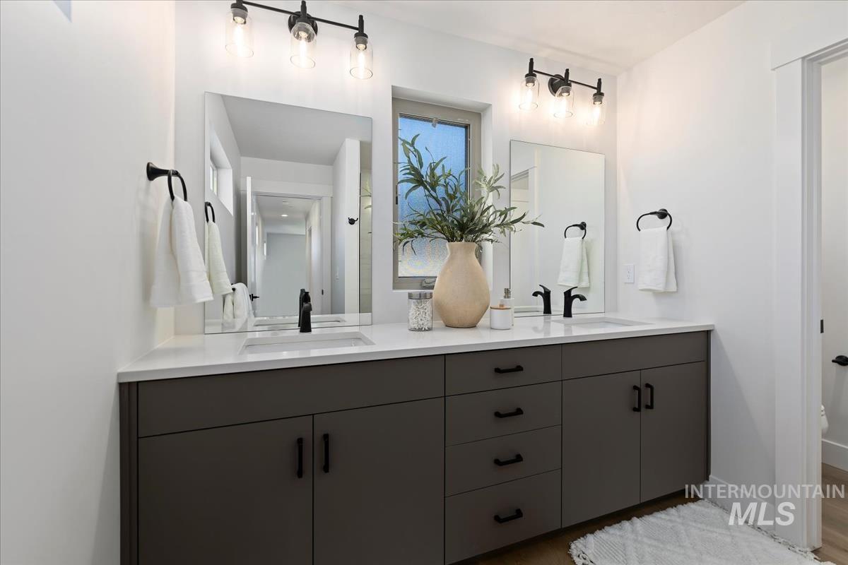Full bathroom with double vanity and wood finished floors