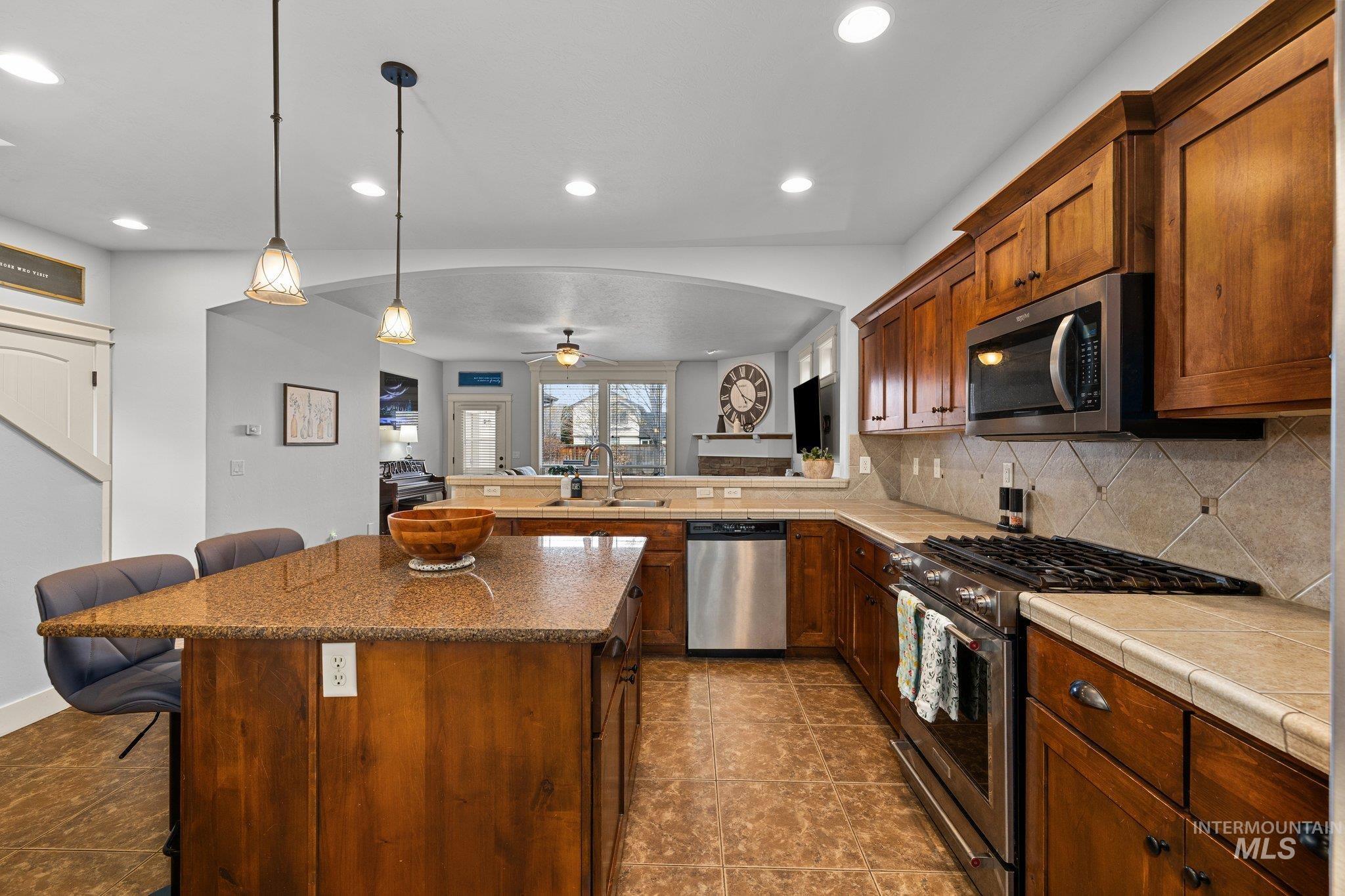 Kitchen featuring a kitchen breakfast bar, stainless steel appliances, tasteful backsplash, pendant lighting, and a peninsula