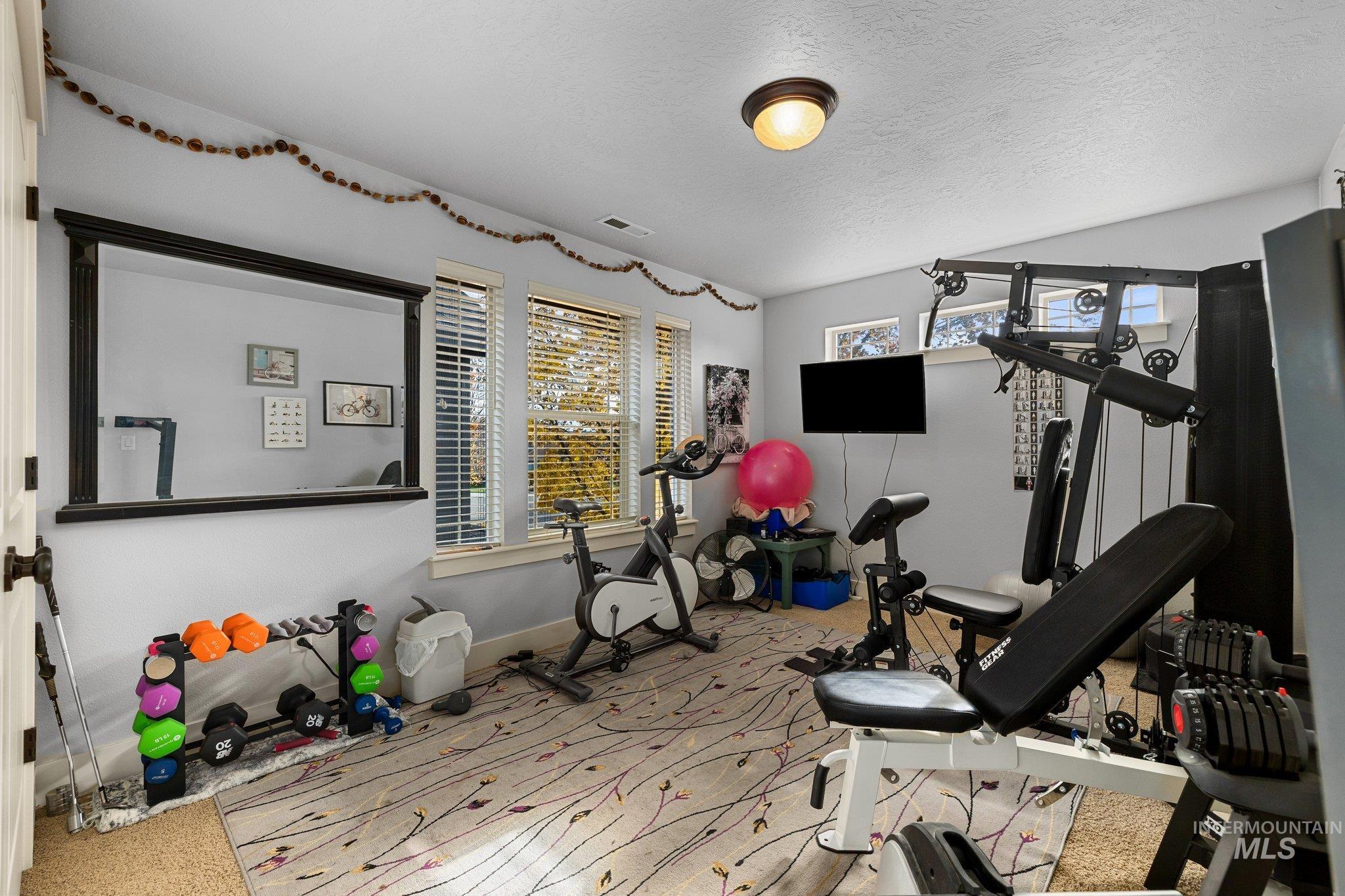 Workout area featuring a textured ceiling and light colored carpet