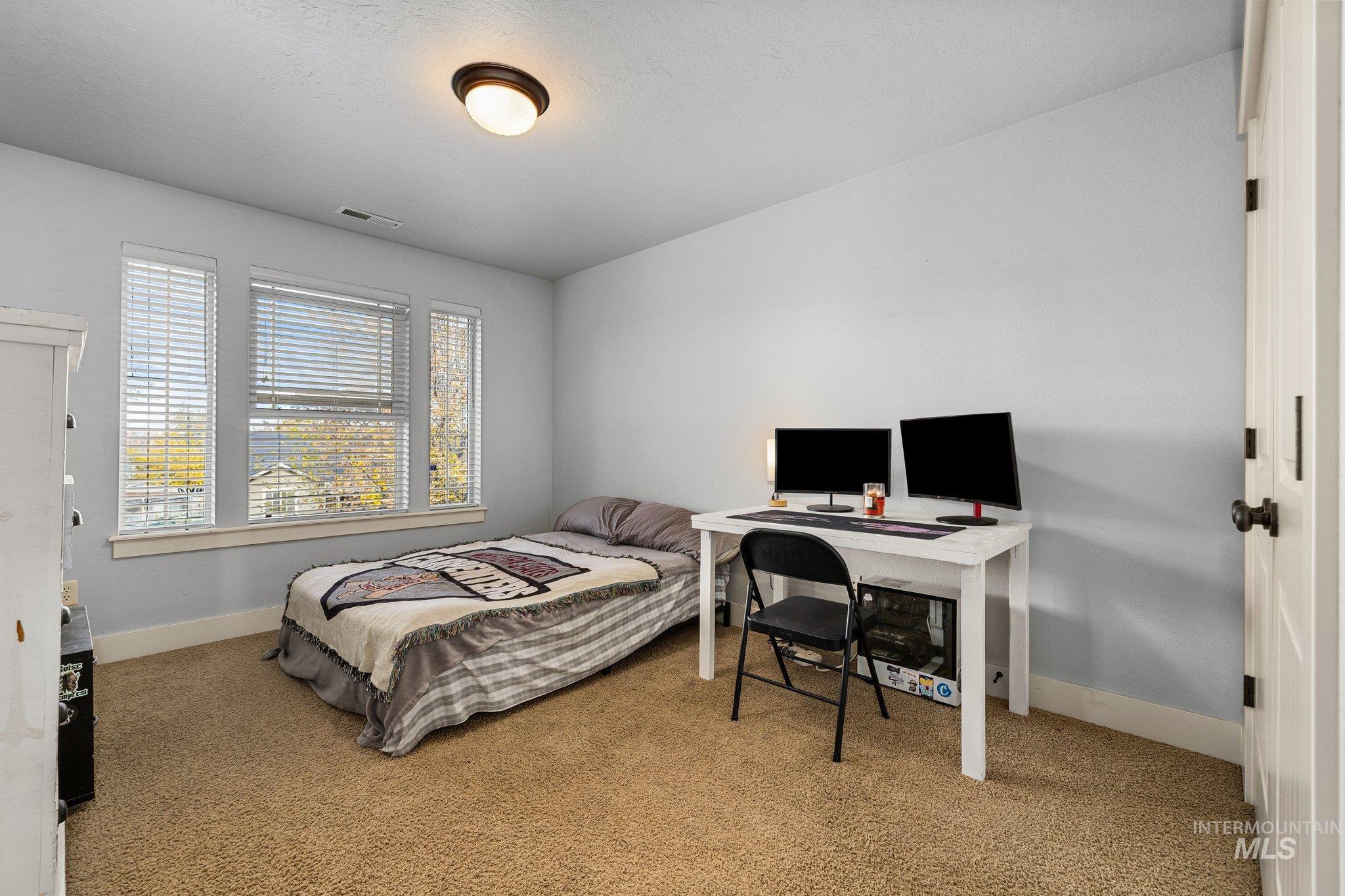 Bedroom featuring light colored carpet and a desk