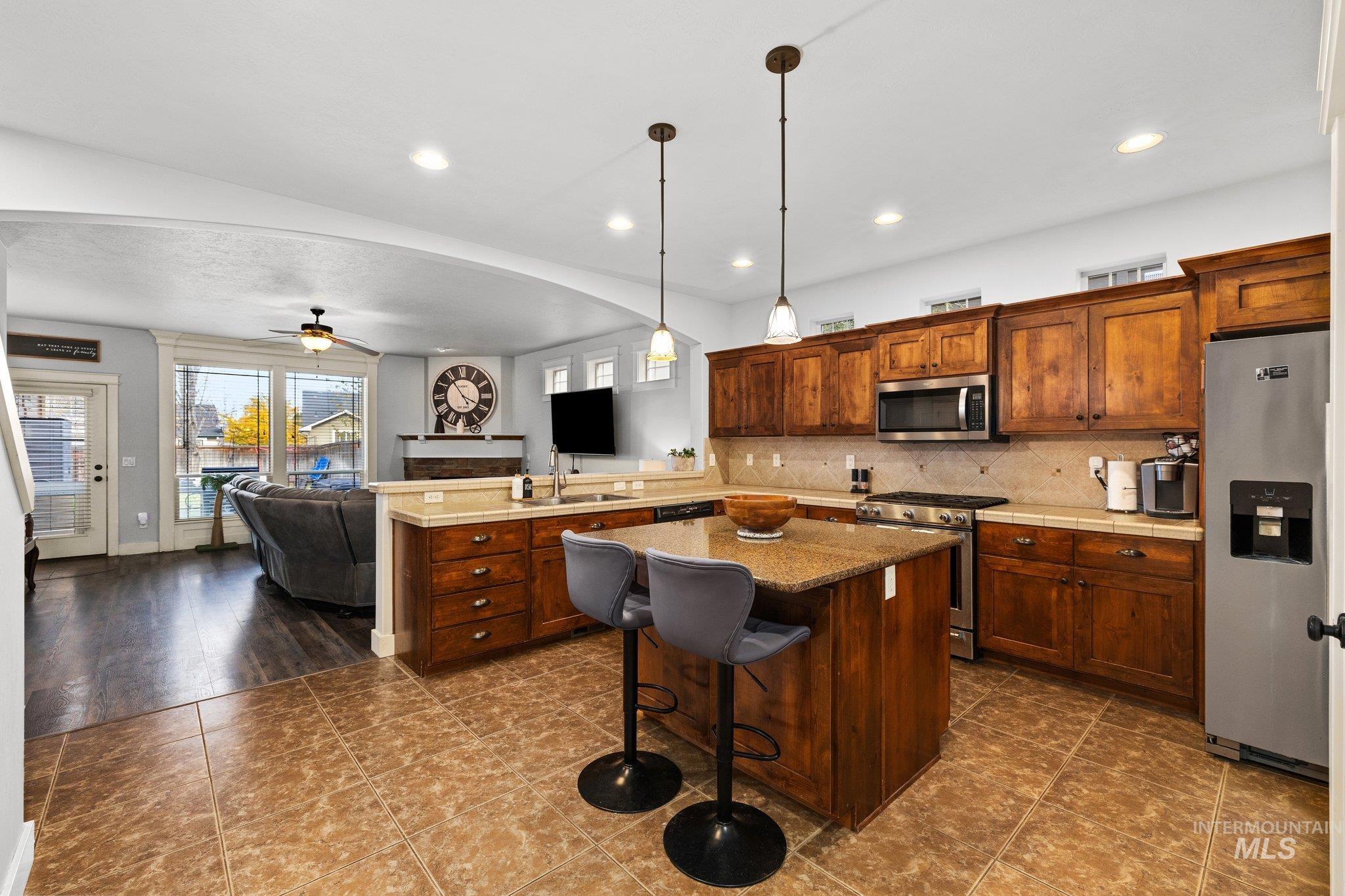 Kitchen with a ceiling fan, a breakfast bar, open floor plan, tasteful backsplash, and hanging light fixtures