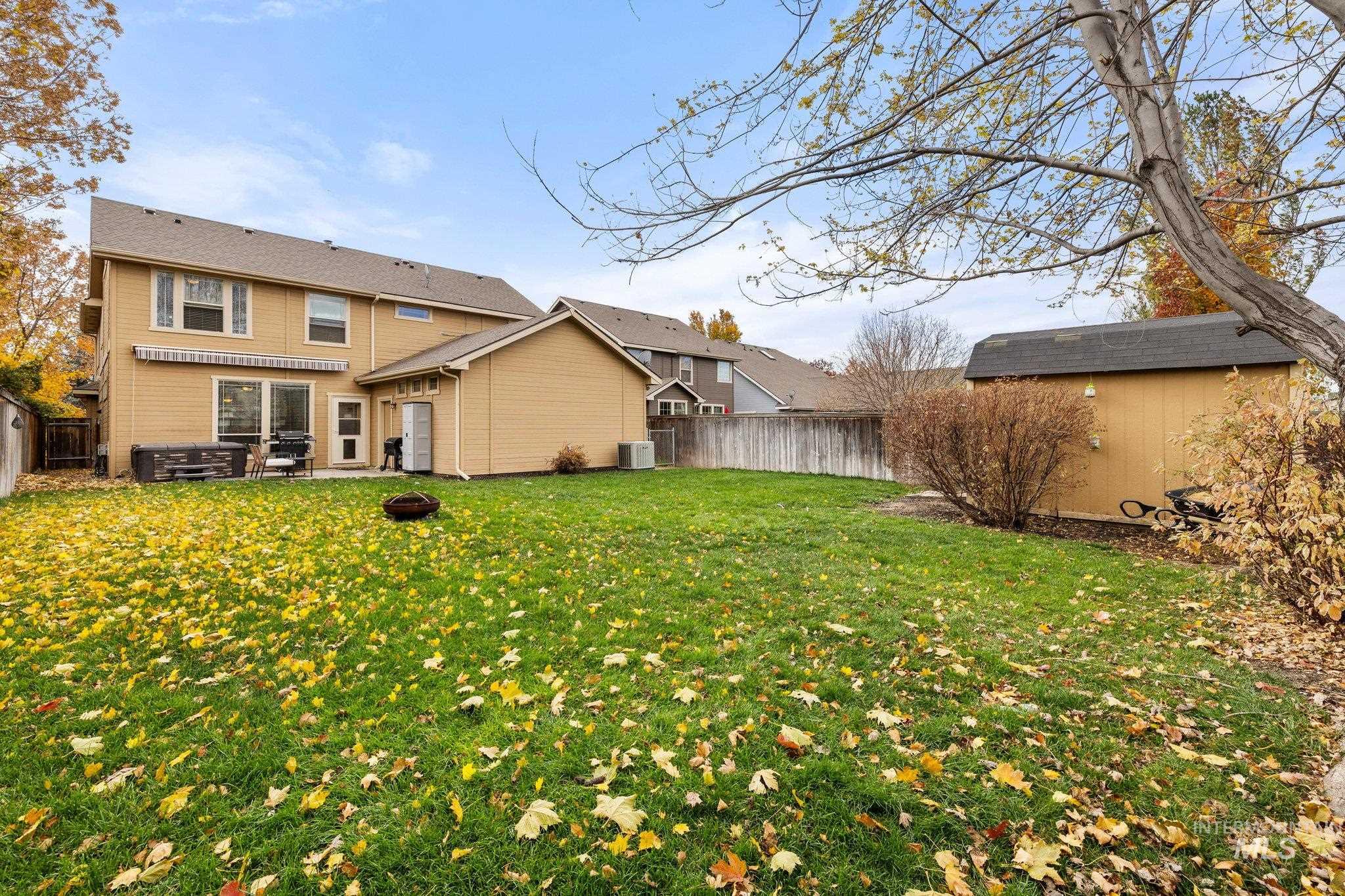 Back of property featuring a storage unit, a fenced backyard, and a fire pit