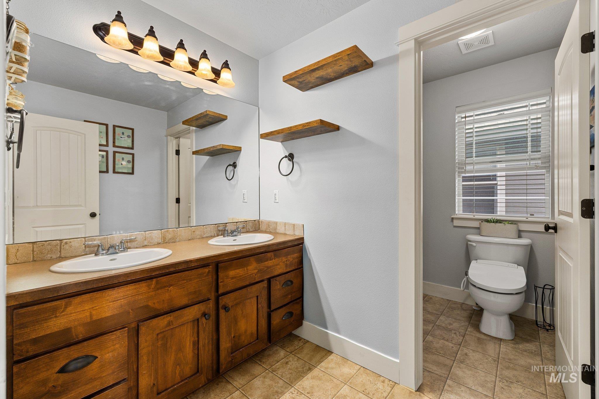 Full bathroom featuring double vanity and light tile patterned flooring