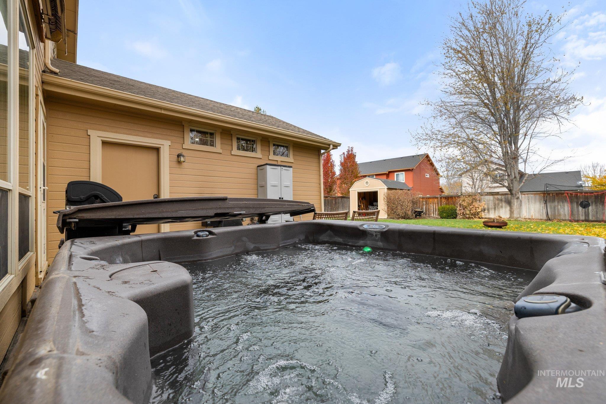 View of pool with a hot tub, a fenced backyard, area for grilling, and an outbuilding