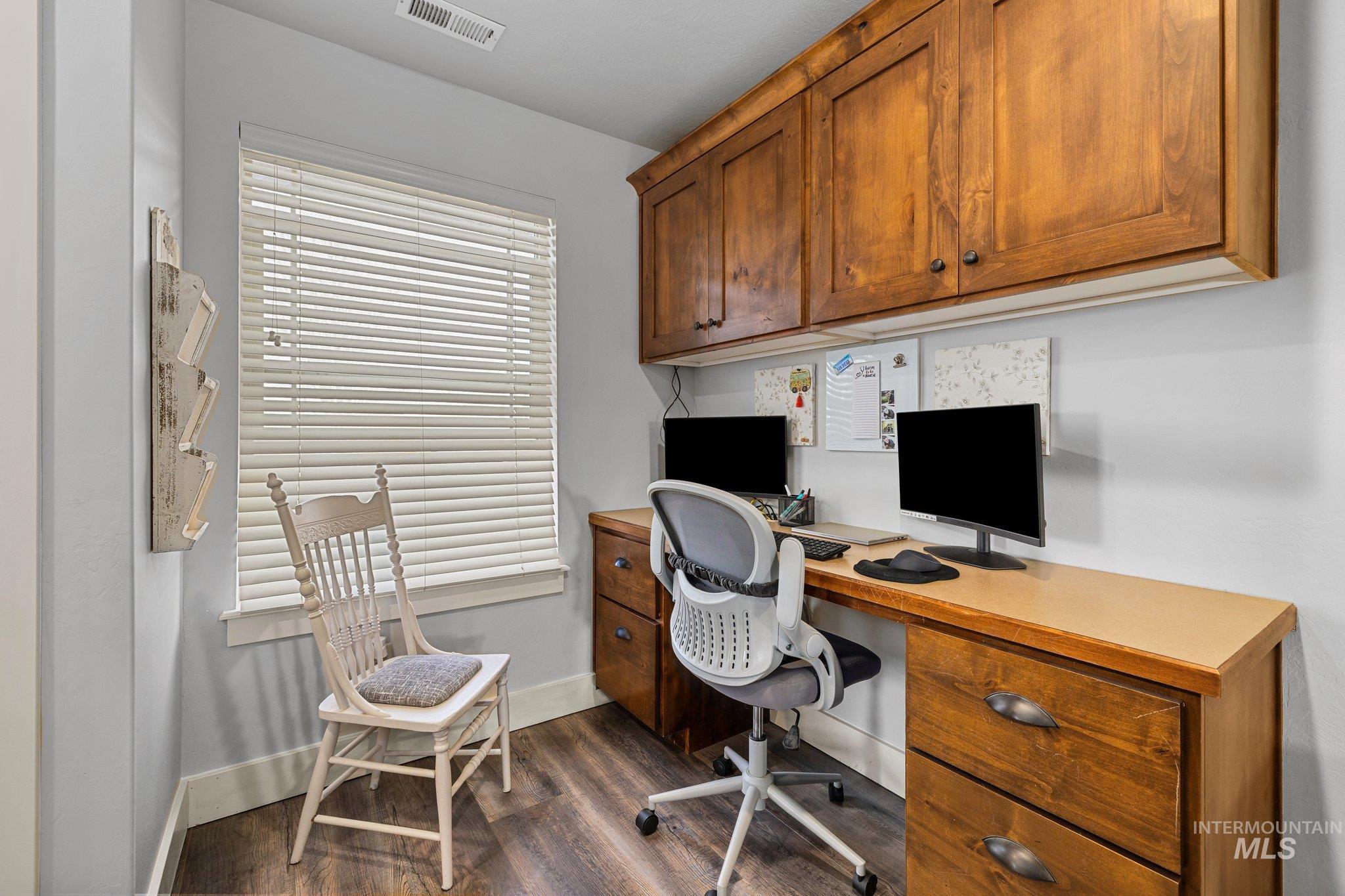Office area with dark wood-style floors and baseboards
