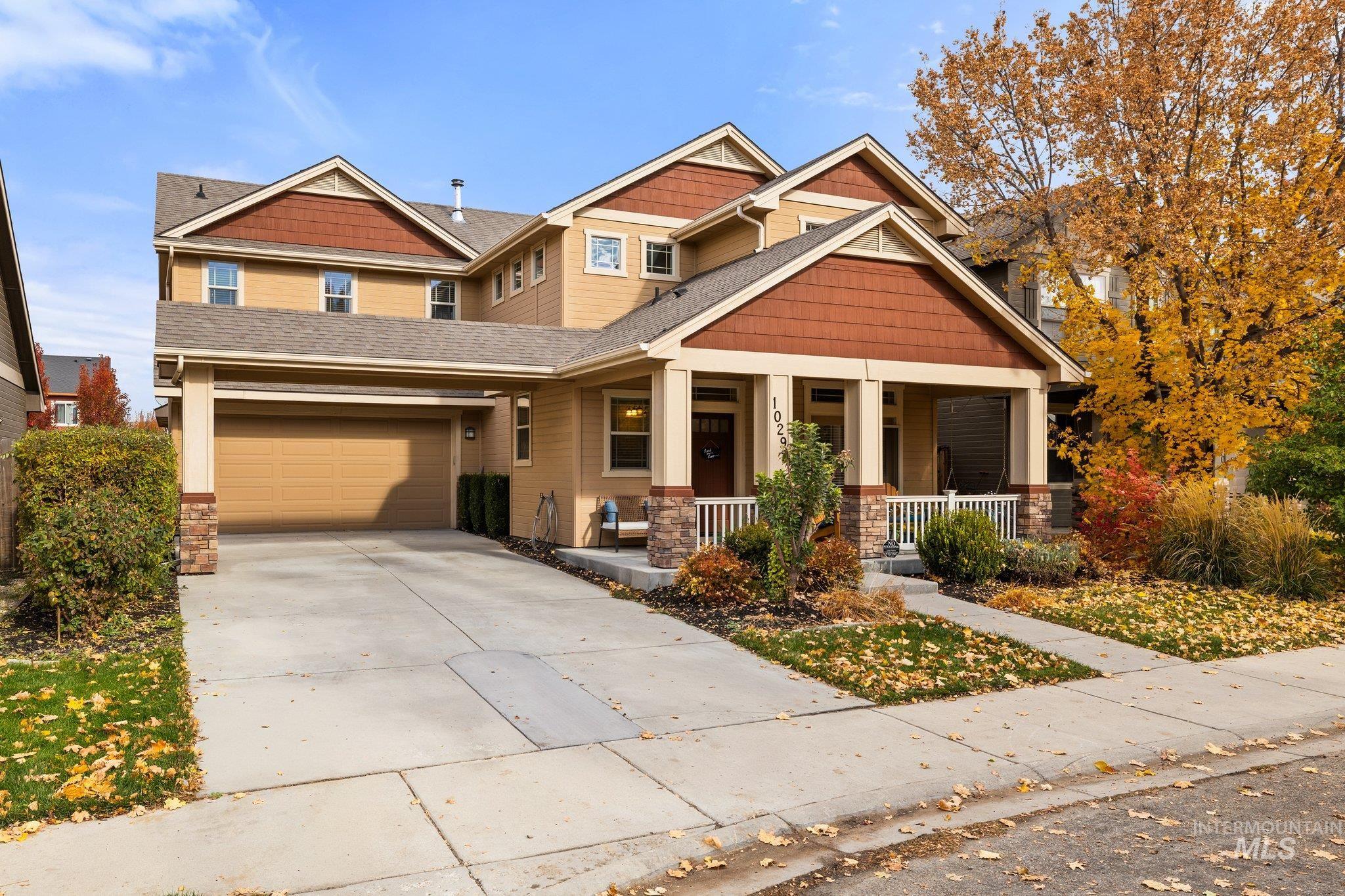 Craftsman-style home with covered porch, stone siding, driveway, a shingled roof, and an attached garage