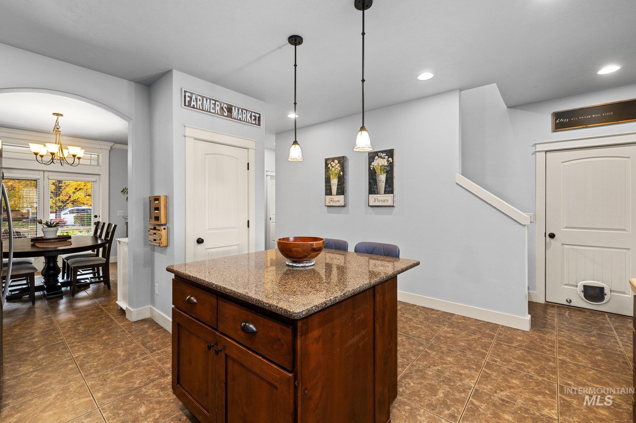 Kitchen with dark stone counters, a chandelier, a kitchen island, pendant lighting, and recessed lighting