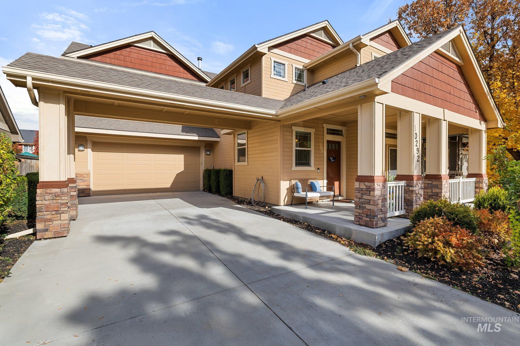 Craftsman-style home featuring stone siding, roof with shingles, covered porch, and concrete driveway