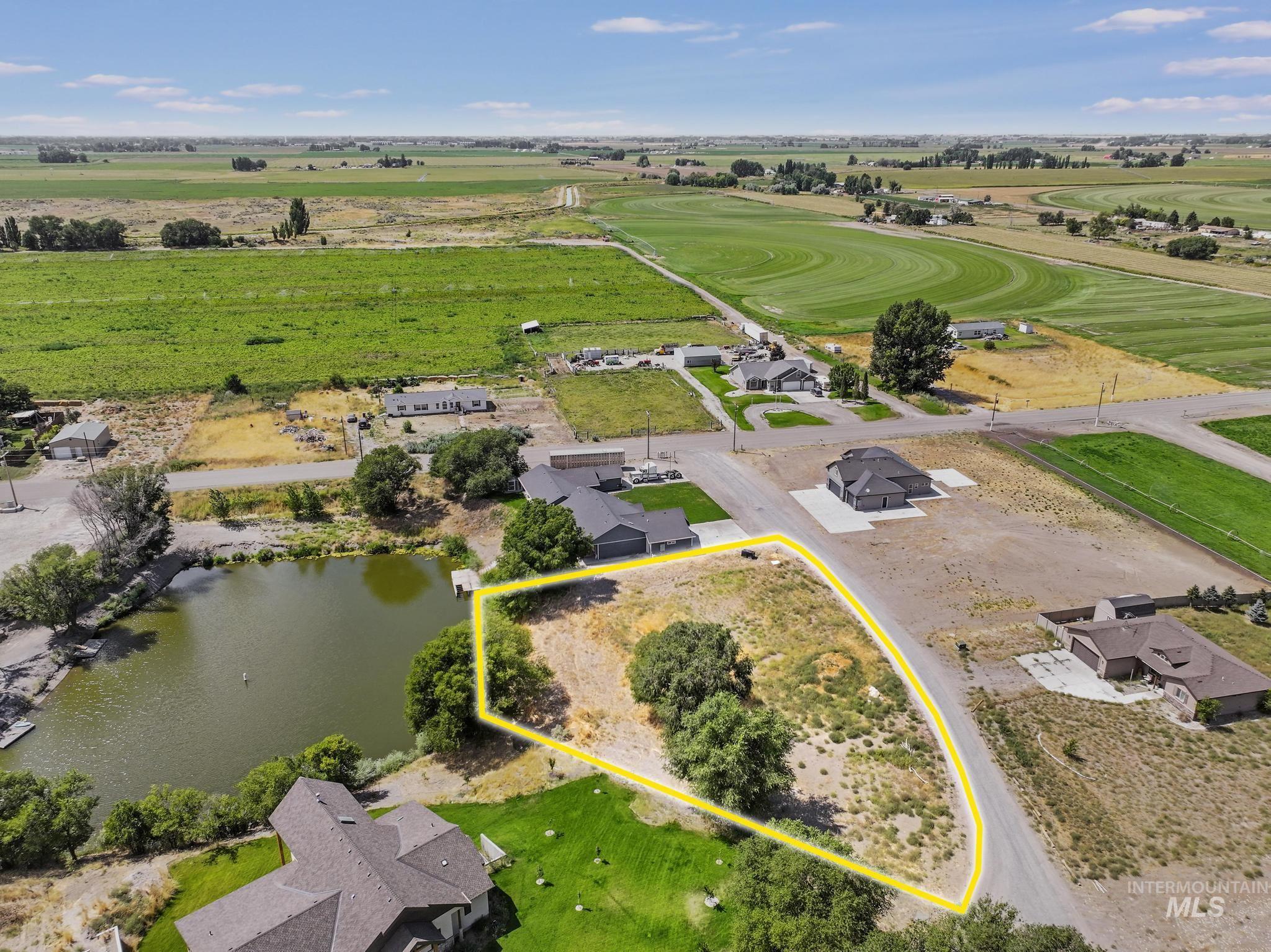 Aerial view of sparsely populated area featuring a nearby body of water and property parcel outlined