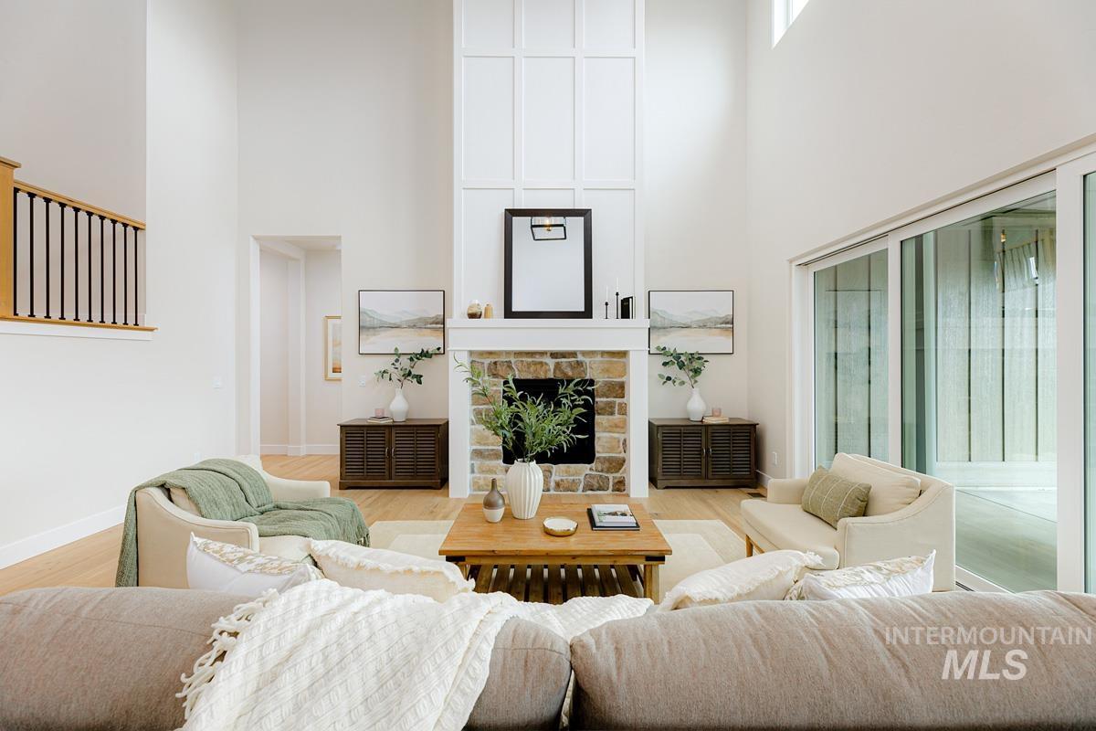 Living room featuring a towering ceiling, a fireplace, and wood finished floors