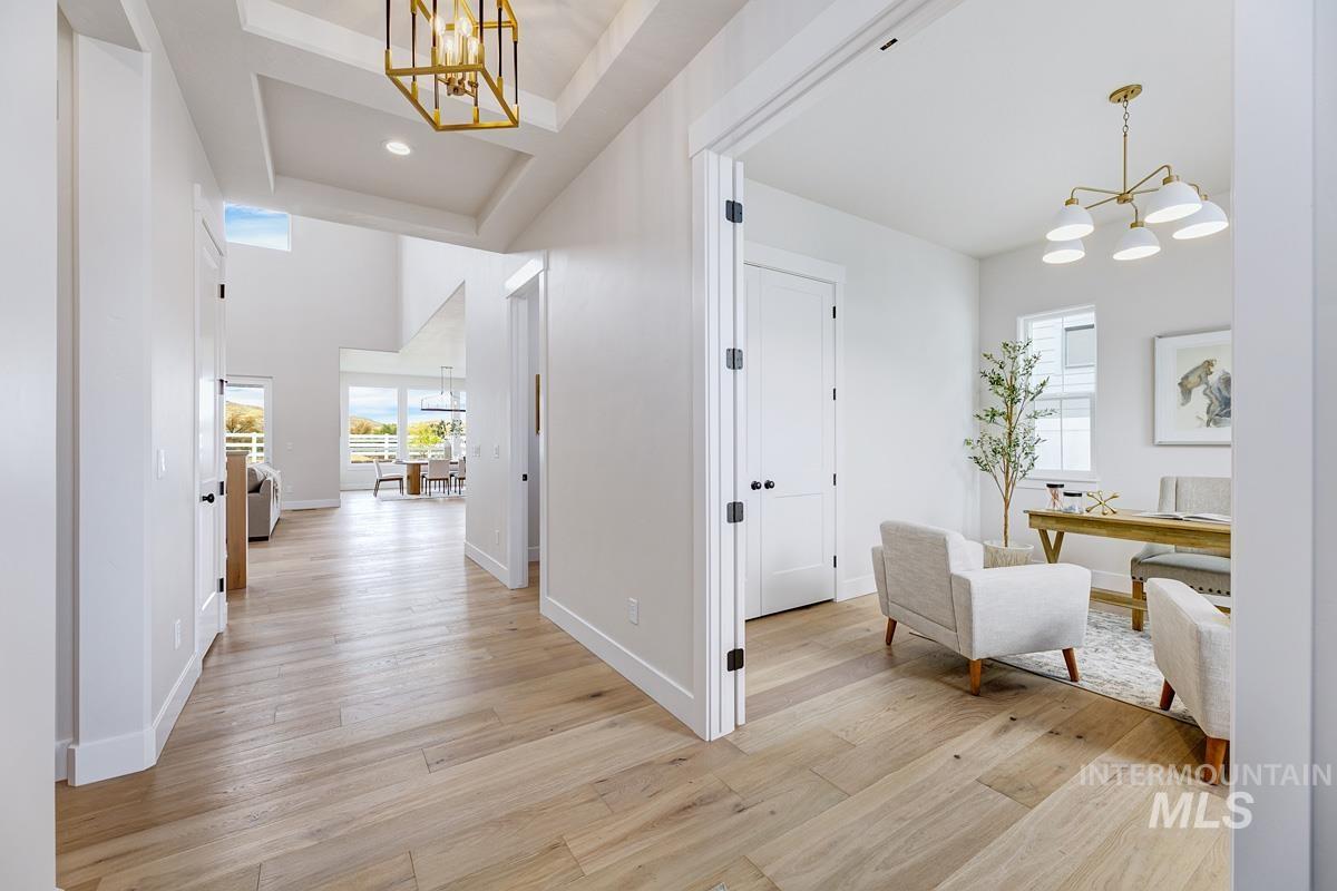 Hall with a chandelier, light wood-style flooring, an office area, and a towering ceiling