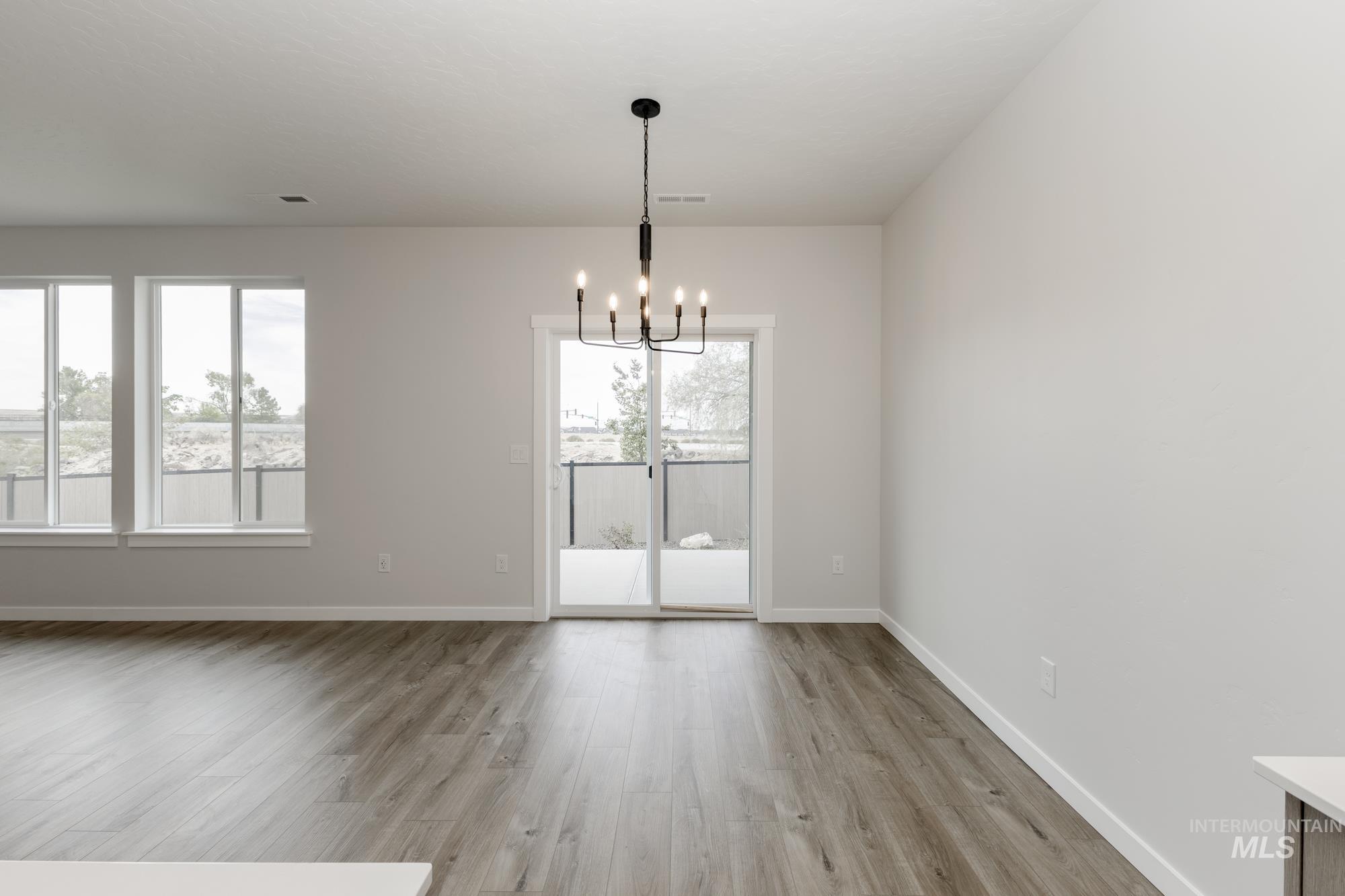 Unfurnished dining area with plenty of natural light, light wood finished floors, and a chandelier