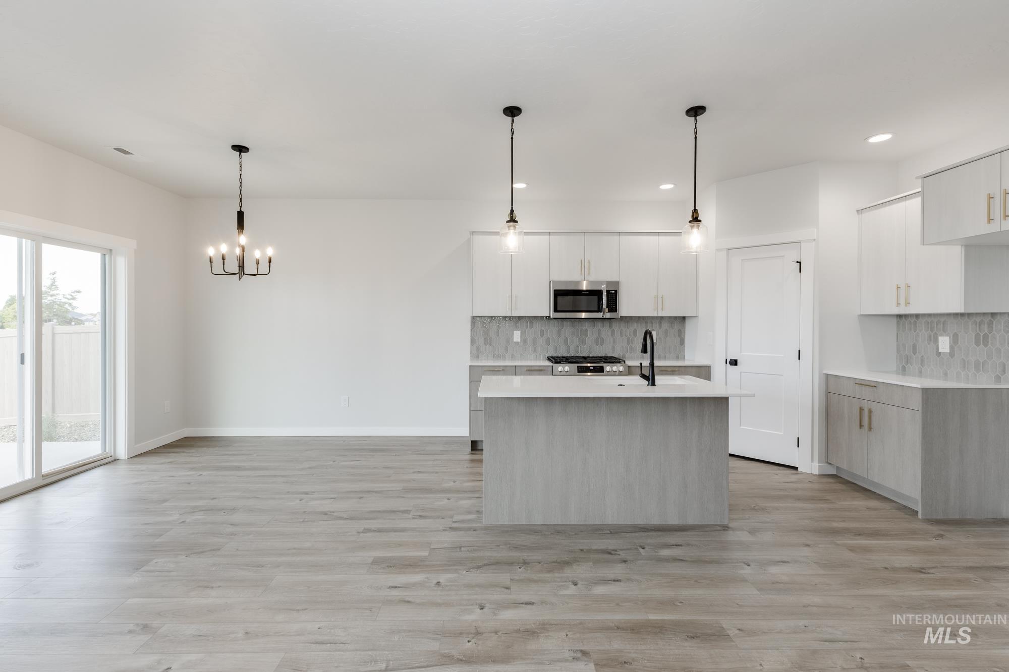 Kitchen featuring white cabinetry, an island with sink, light wood-style flooring, decorative backsplash, and recessed lighting