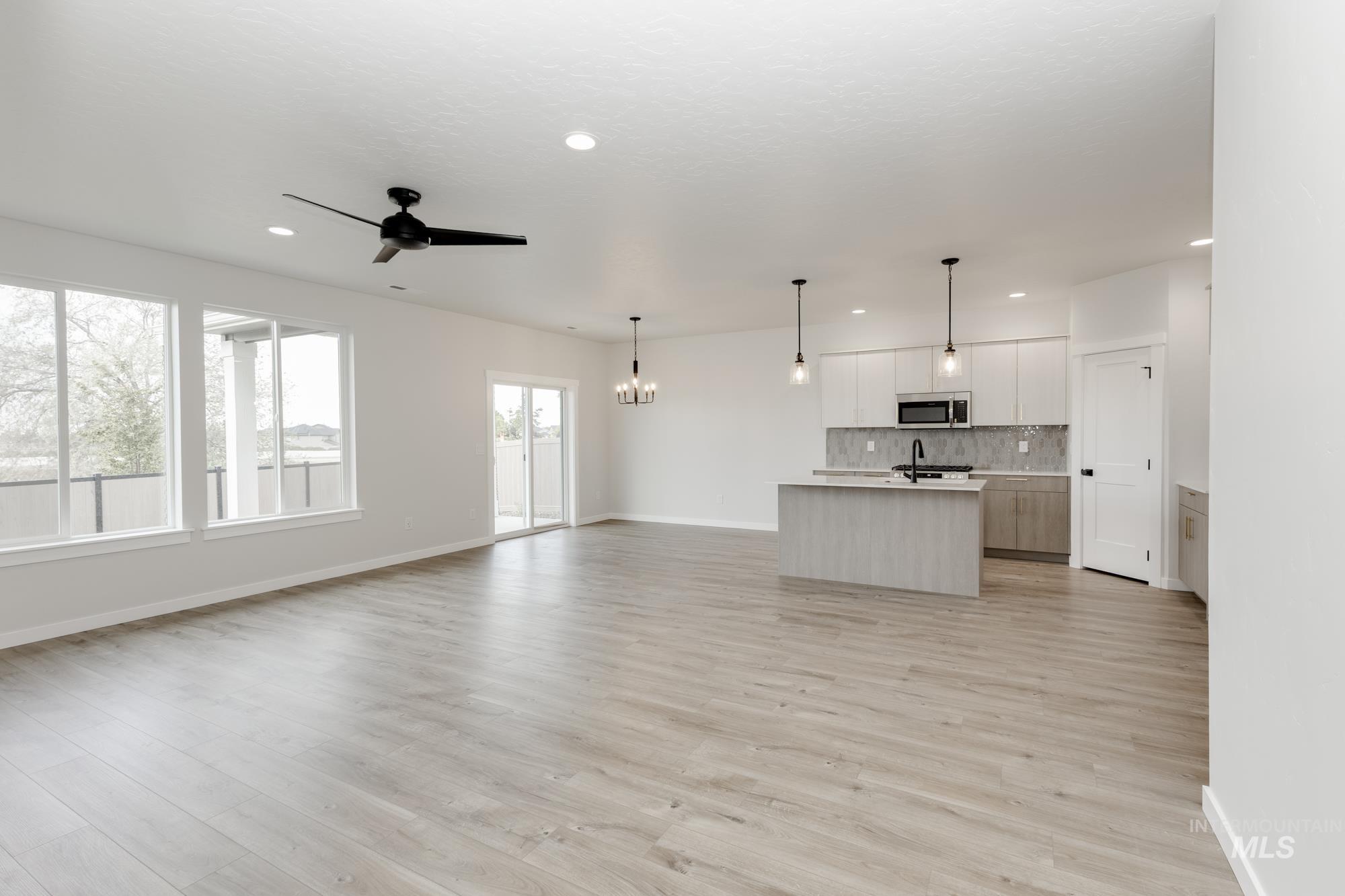 Unfurnished living room featuring light wood-style floors, a ceiling fan, recessed lighting, and a chandelier