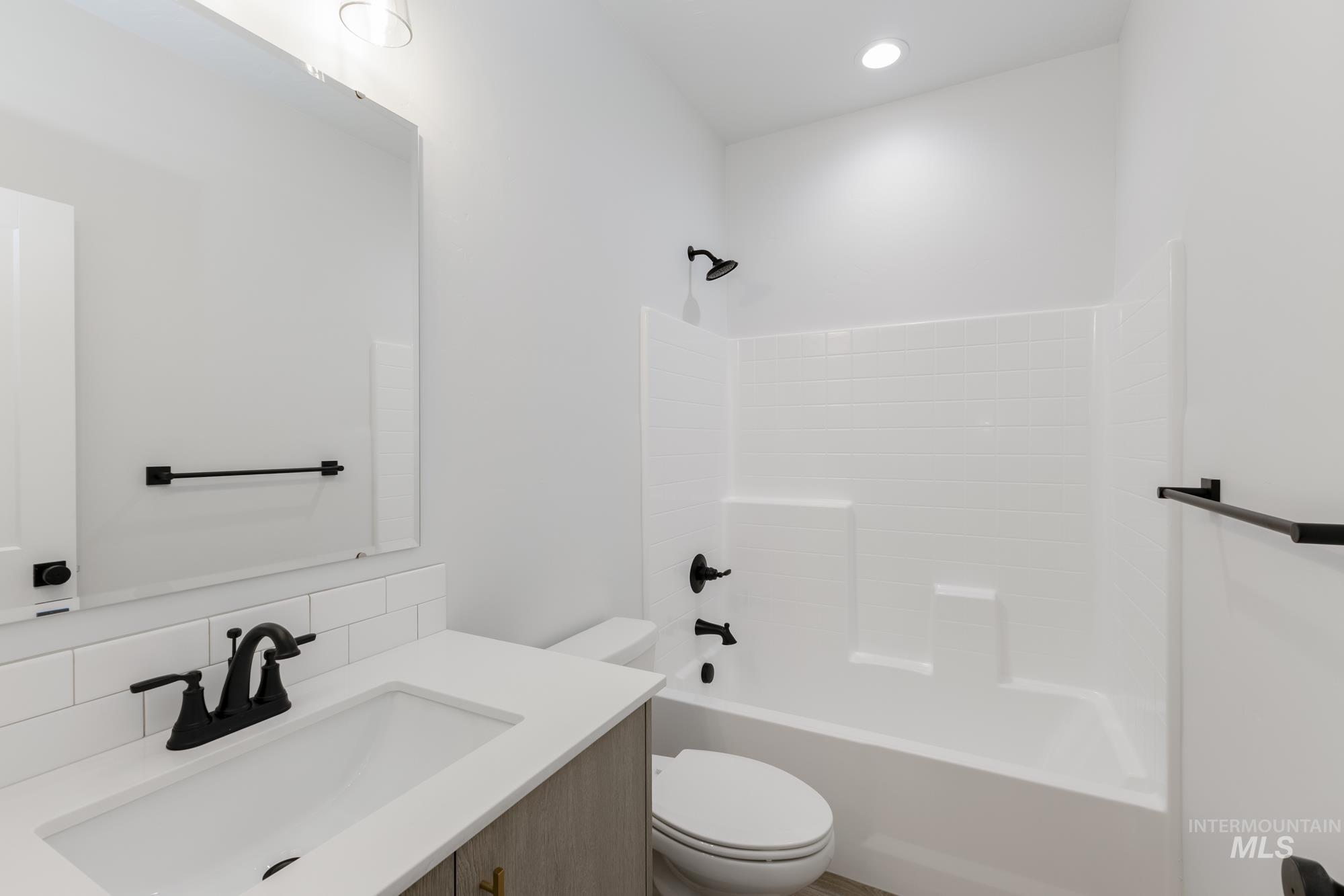 Bathroom featuring vanity, washtub / shower combination, and tasteful backsplash