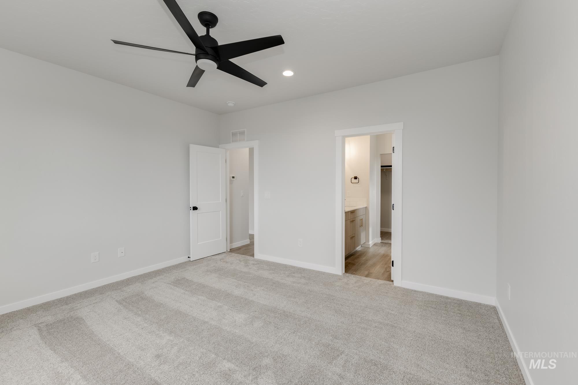 Unfurnished bedroom featuring light colored carpet, a ceiling fan, recessed lighting, and ensuite bath