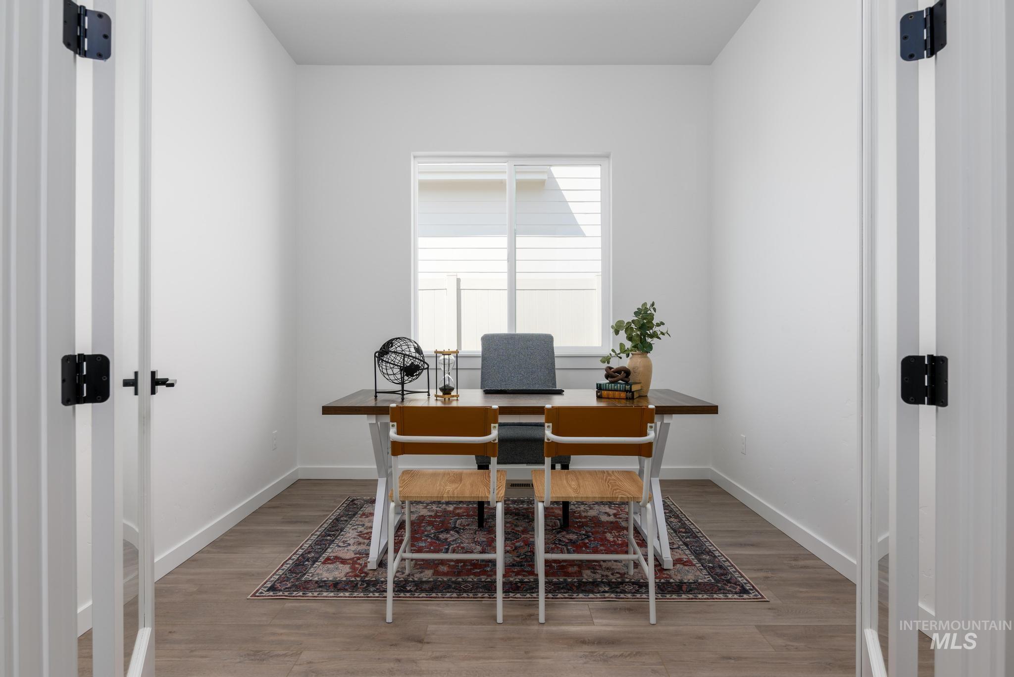 Bright room featuring a window, wood-finish flooring, white walls, and white trim