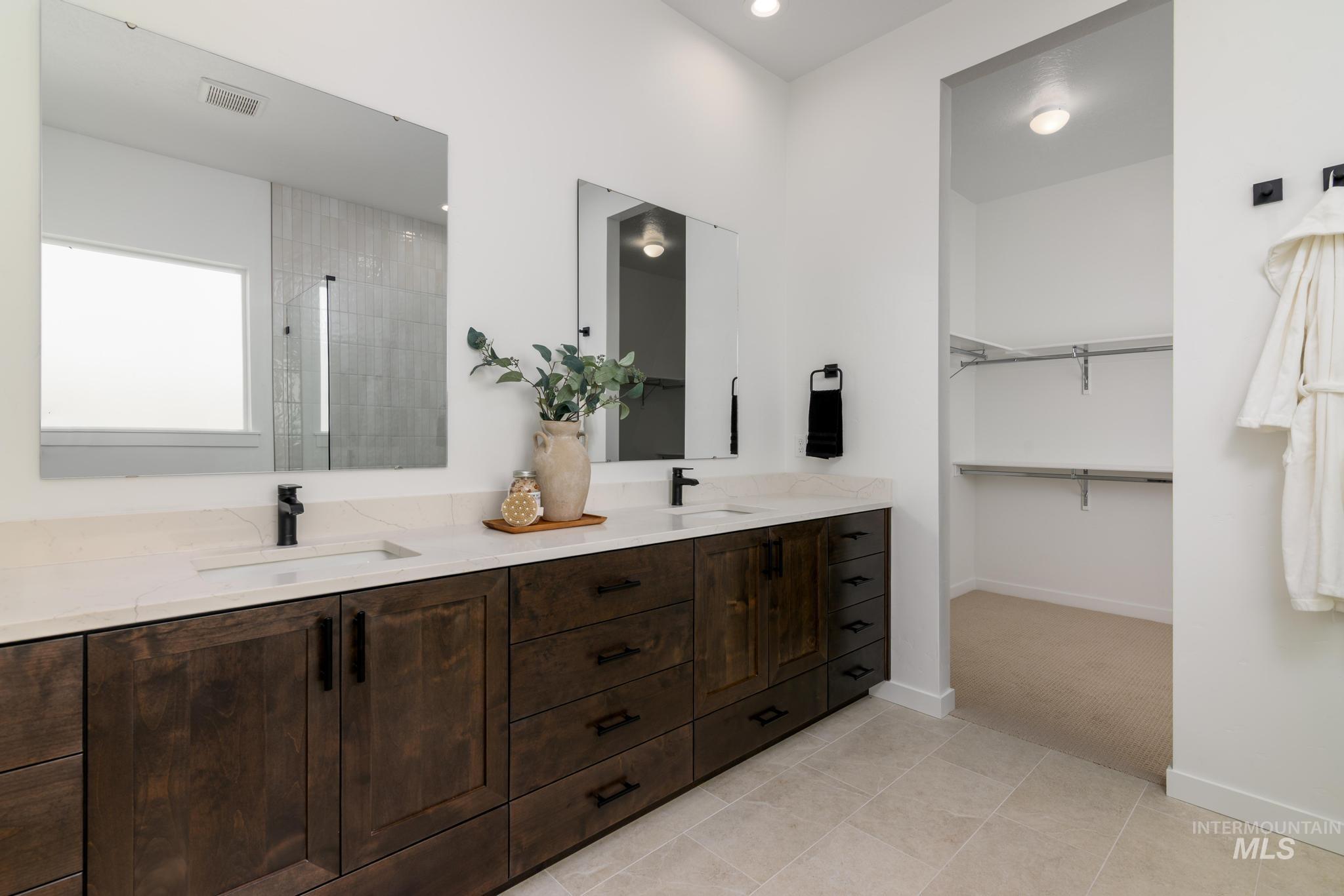 Dual vanity featuring dark wood cabinetry, integrated sinks, light-toned countertops, and matte black fixtures