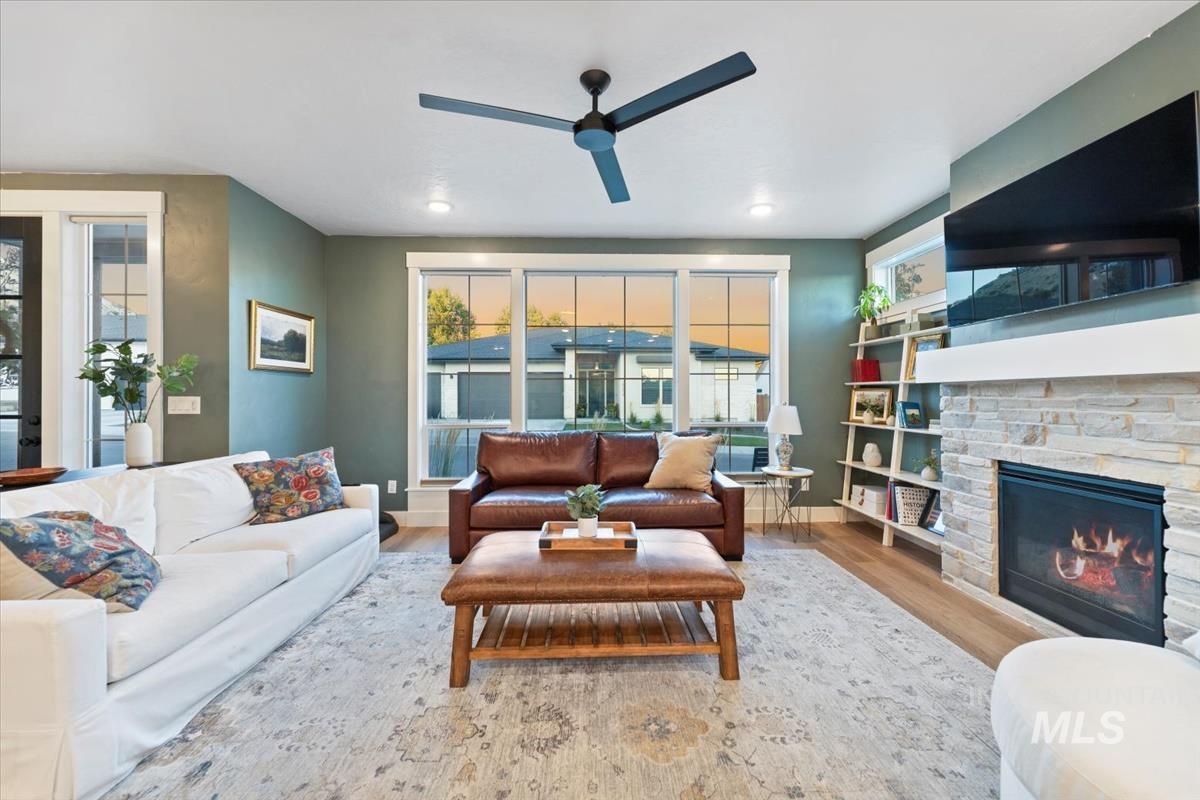 Living area with wood finished floors, a fireplace, and a ceiling fan