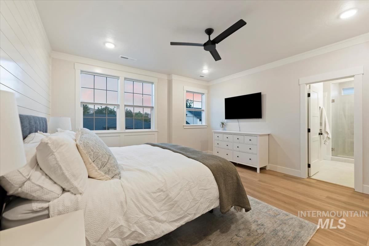 Bedroom with crown molding, light wood finished floors, a ceiling fan, ensuite bathroom, and recessed lighting
