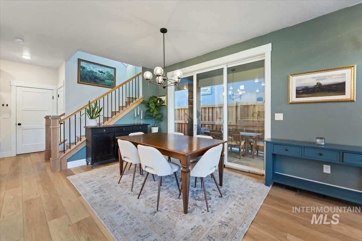 Dining room with stairway, light wood-style flooring, and a chandelier