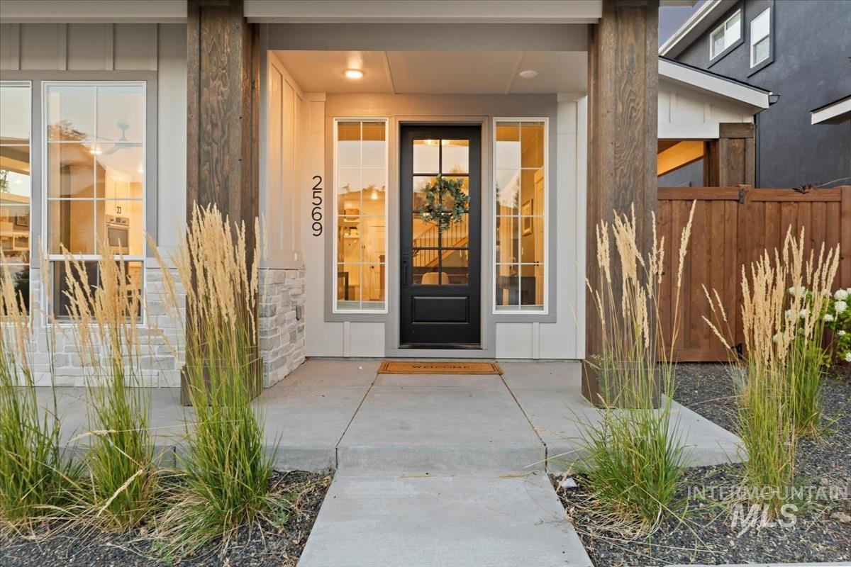 View of exterior entry with covered porch, stone siding, and board and batten siding