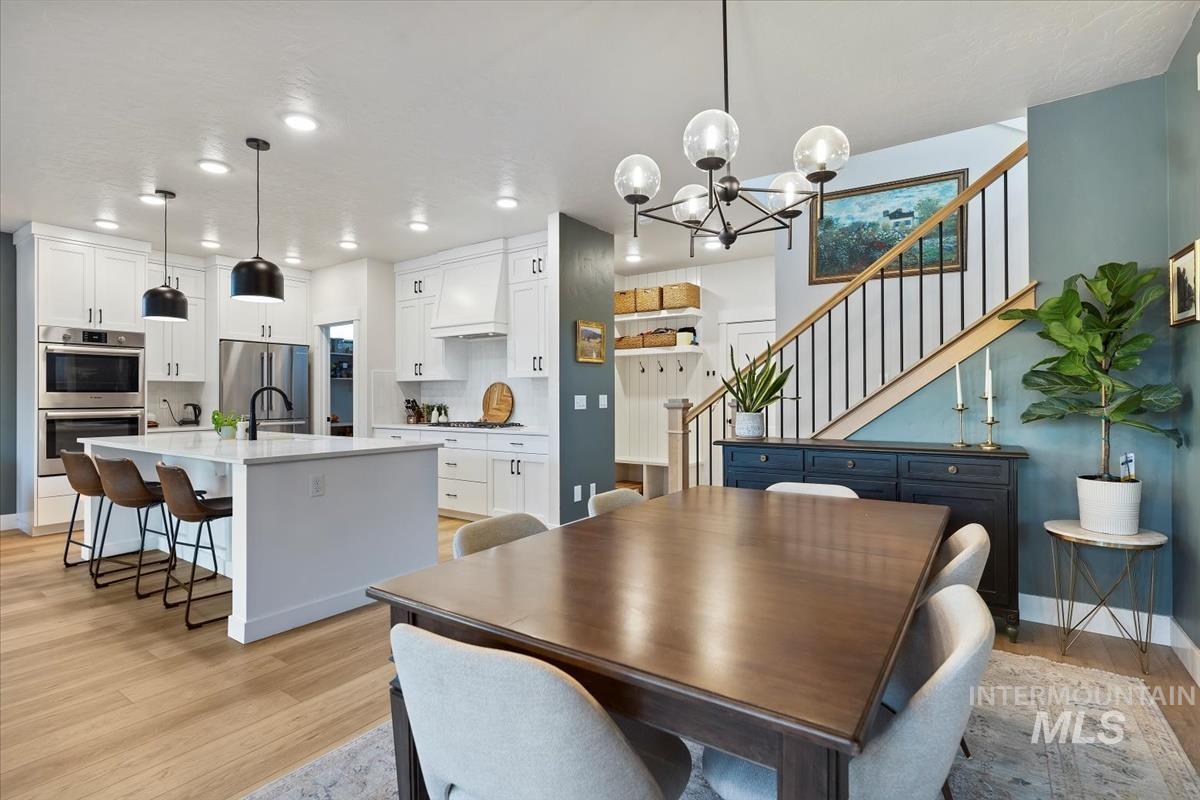 Dining space featuring stairs, light wood finished floors, a chandelier, and recessed lighting
