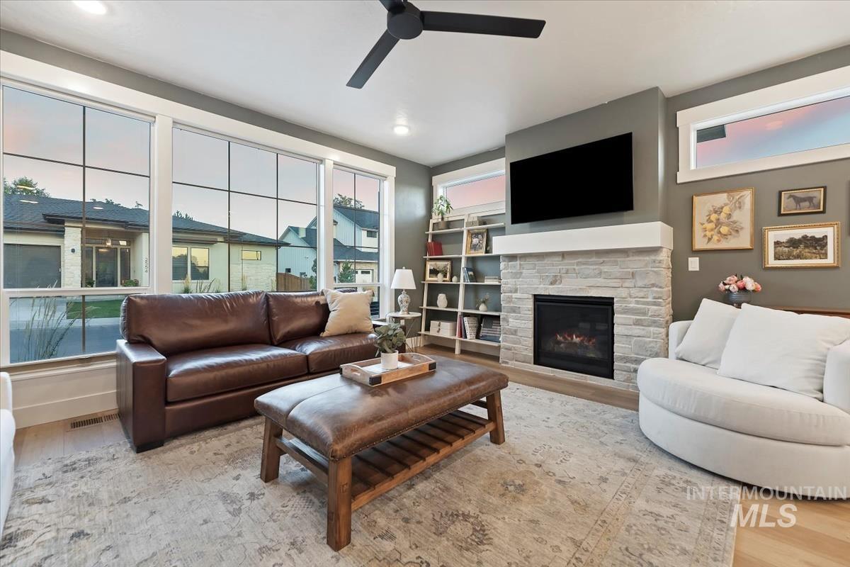 Living area featuring light wood-type flooring, a fireplace, and a ceiling fan