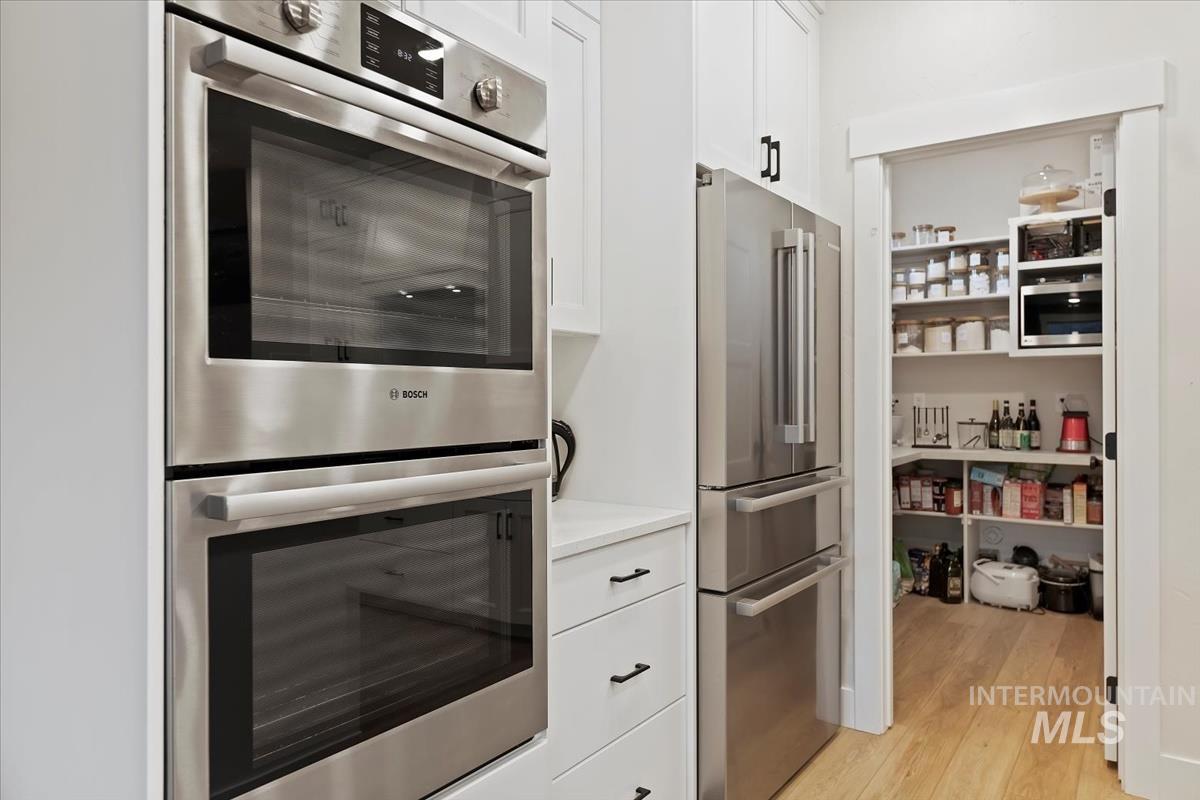 Kitchen featuring stainless steel appliances, white cabinetry, and light wood-style floors