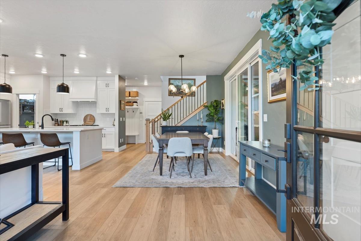 Dining area featuring a chandelier, light wood finished floors, stairs, and recessed lighting