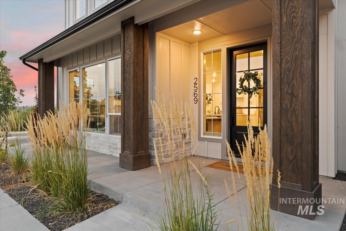 Exterior entry at dusk featuring stone siding, board and batten siding, and a porch