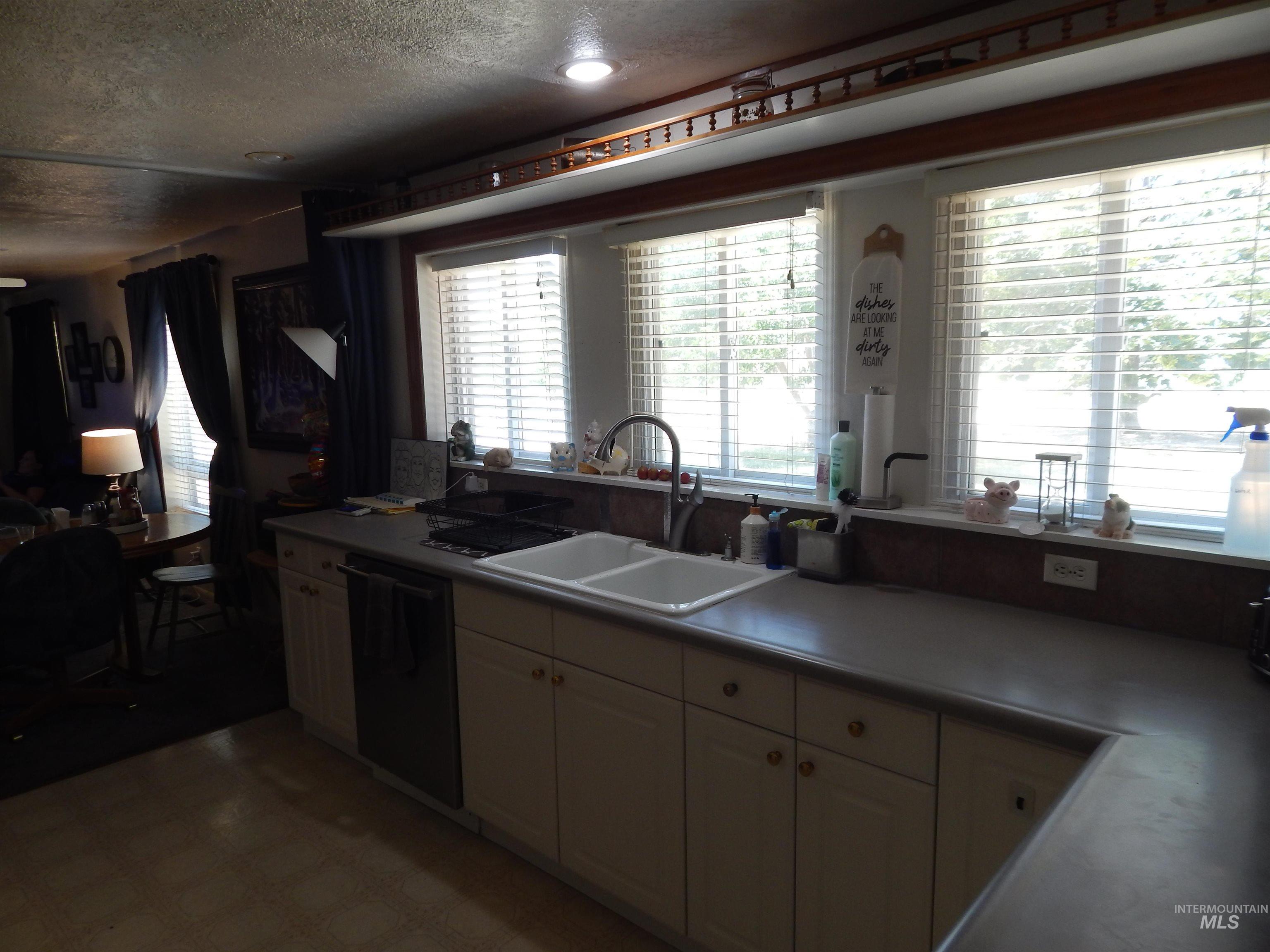 Kitchen with light floors, dishwasher, a textured ceiling, and light countertops