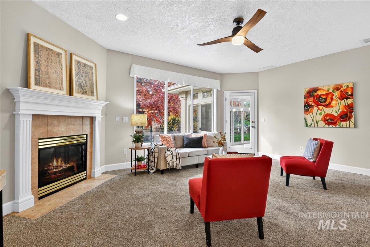 Carpeted living room featuring a textured ceiling, a fireplace, and ceiling fan