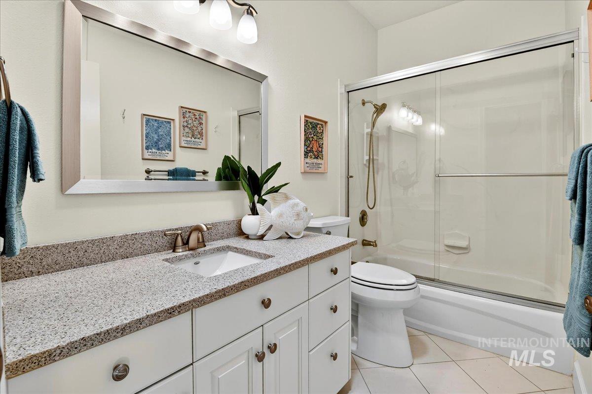 Full bath featuring vanity, light tile patterned floors, and bath / shower combo with glass door
