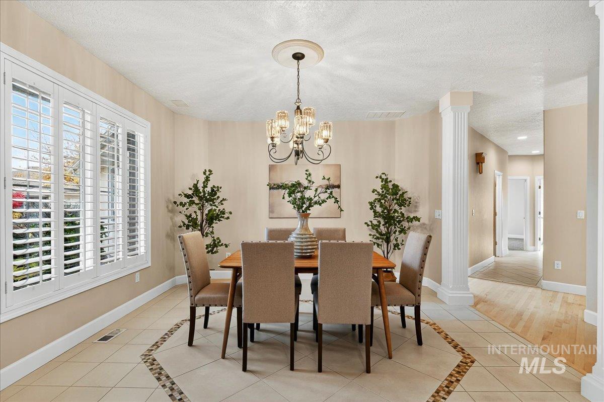 Dining room featuring light tile patterned floors, inlaid floor details, a textured ceiling, and a chandelier