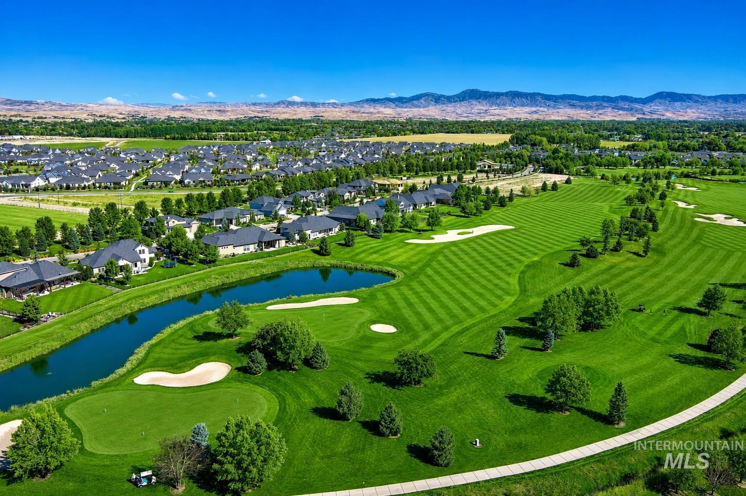Expansive golf course setting featuring manicured fairways, sand traps, and a water feature