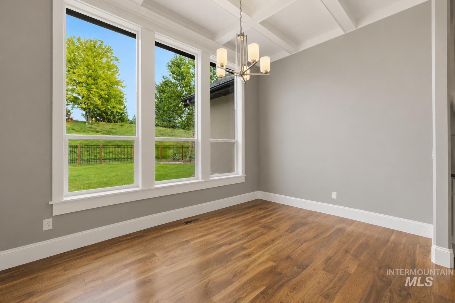 Dining area featuring expansive floor-to-ceiling windows, wood-finish flooring, a coffered ceiling, a modern chandelier with frosted glass shades, and neutral wall tones