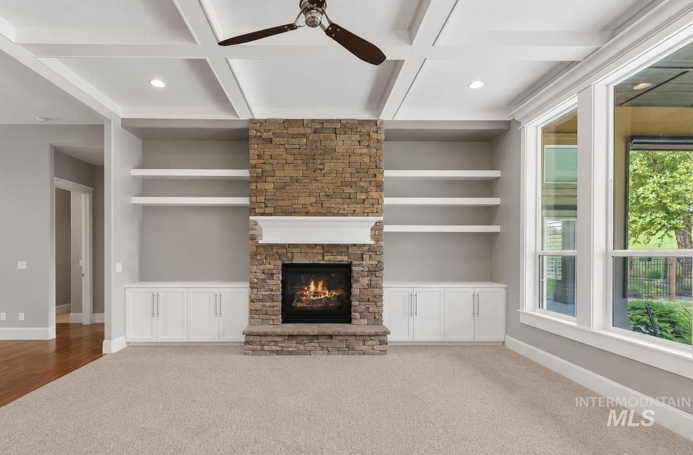 Stone-clad fireplace with mantel and hearth, flanked by built-in shelving and cabinetry
