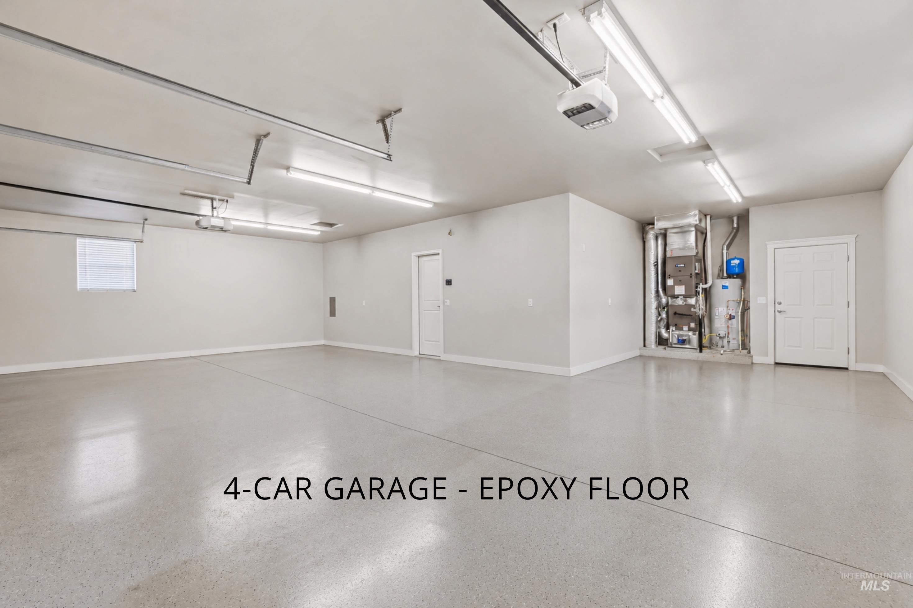Spacious garage featuring an epoxy floor finish, multiple fluorescent lighting fixtures, a side entry door, and a single window