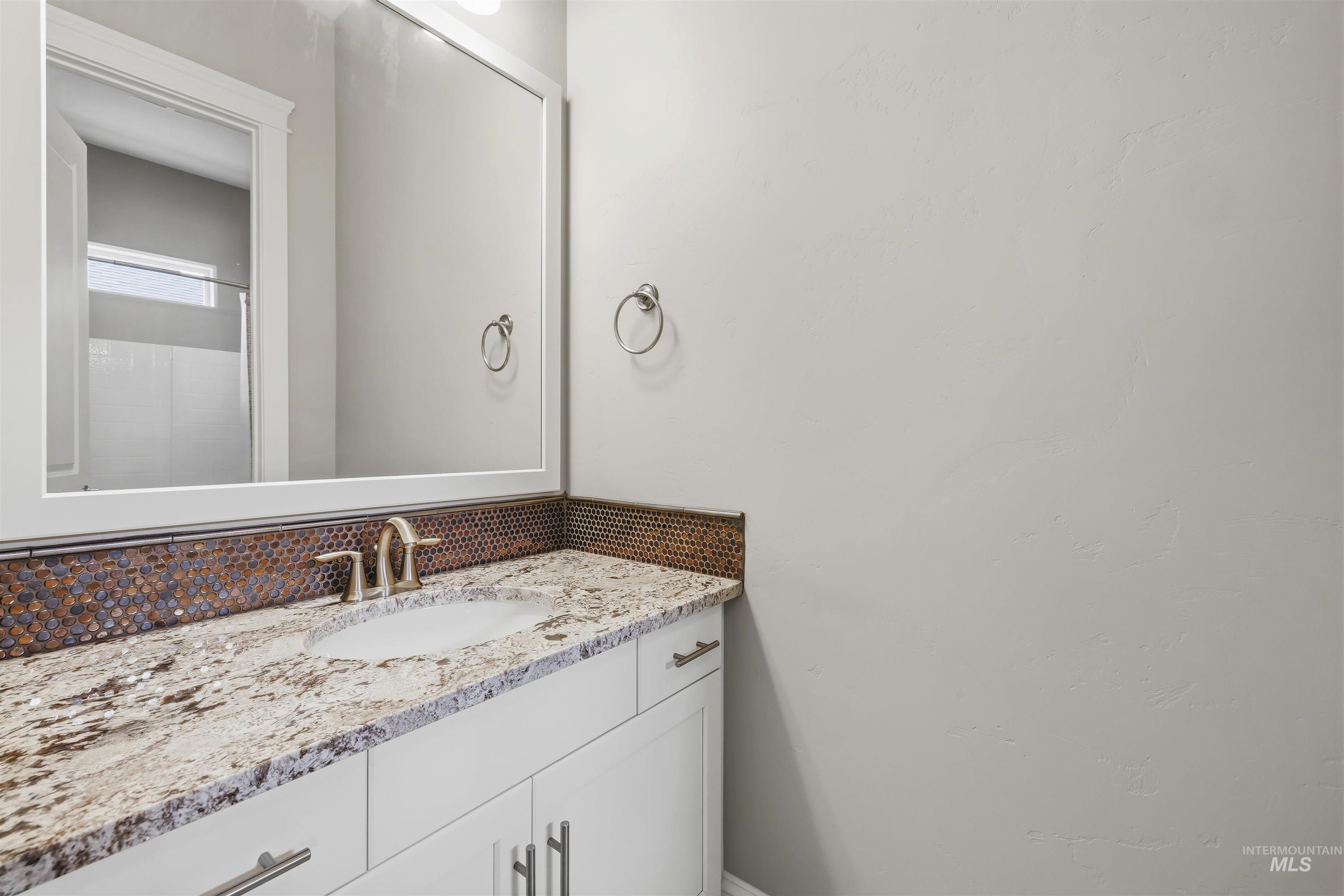 Vanity featuring a stone countertop, an undermount sink, and a brushed nickel faucet