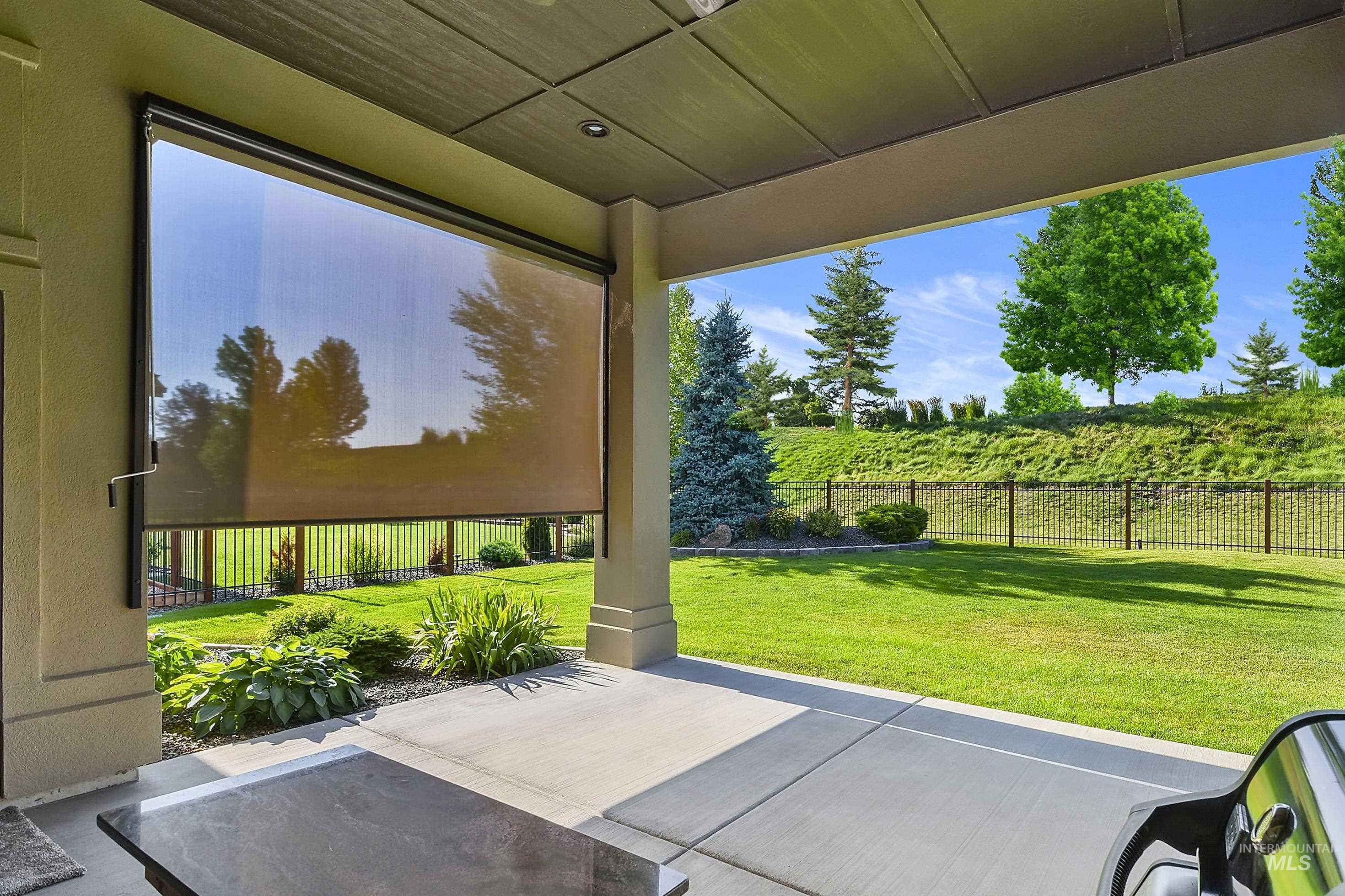 Covered patio featuring a concrete surface, overhead lighting, and an exterior roll-down sunshade
