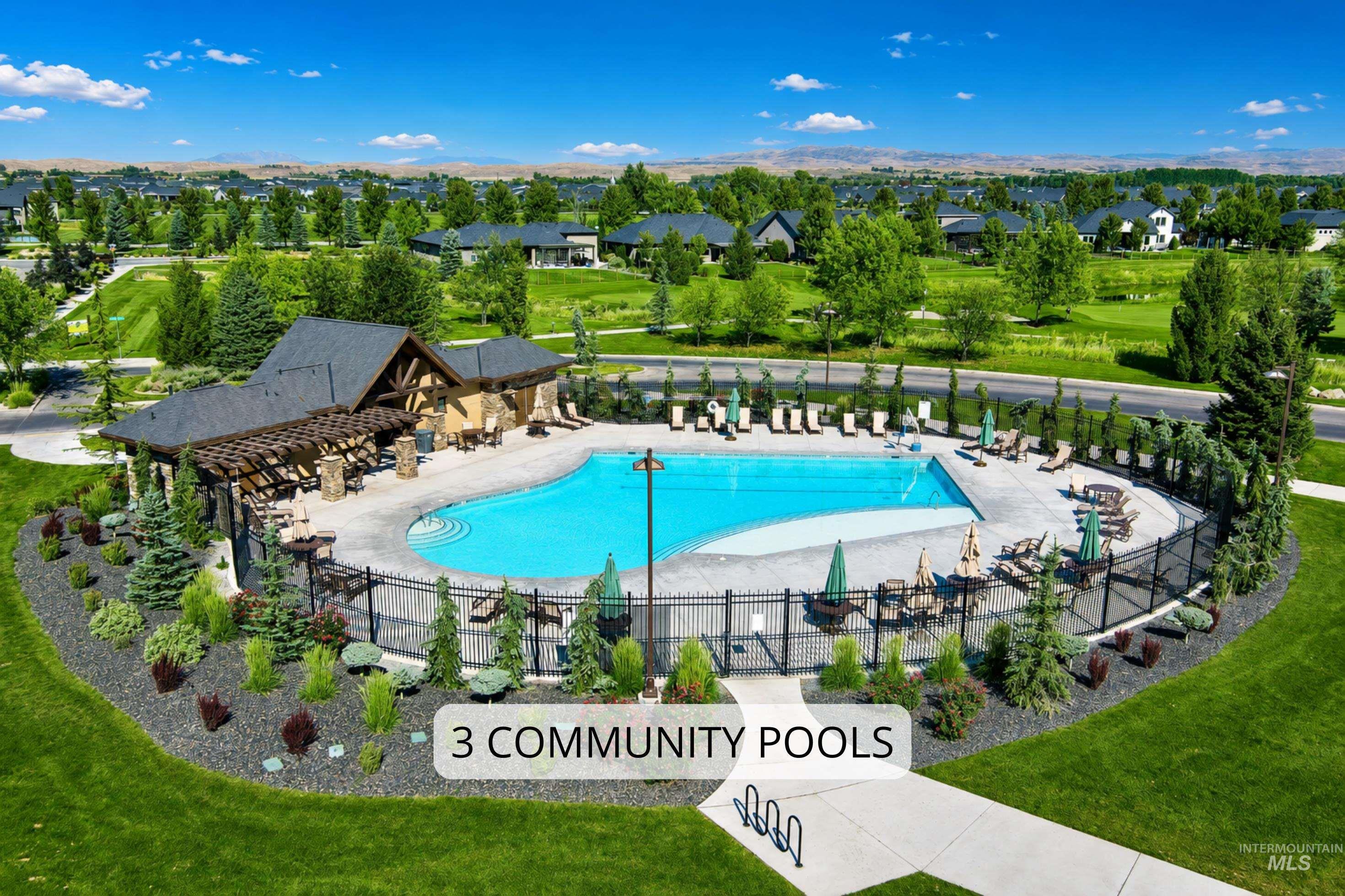 Community pool area featuring a freeform swimming pool, an adjacent clubhouse with exposed timber accents, and a perimeter of mature landscaping