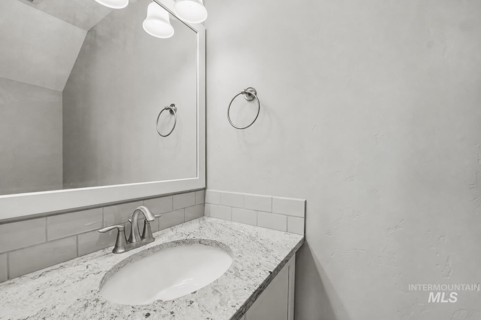 Vanity with a white undermount sink, speckled countertop, and brushed nickel faucet