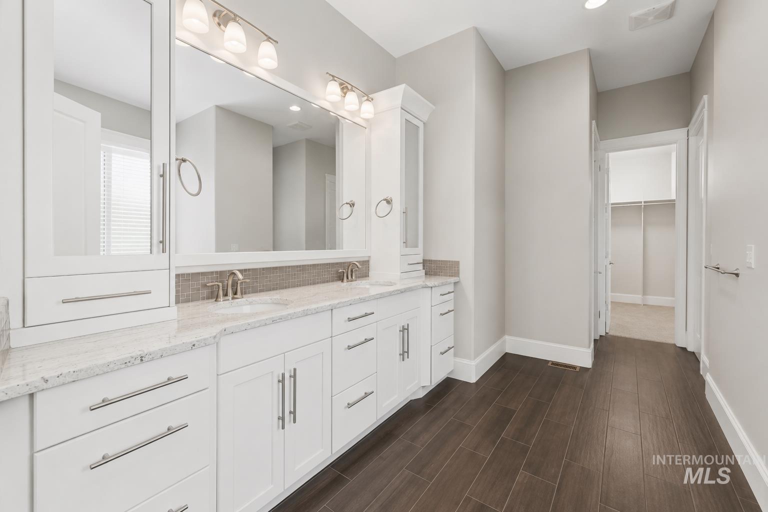 Double vanity featuring white cabinetry, light-toned countertops, and brushed nickel hardware